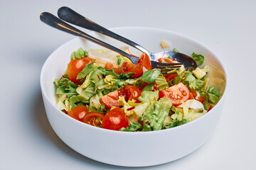 mixed green salad with tomatoes and cheese in a bowl.
