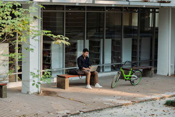 business man sitting on bench and working remotely on project with laptop