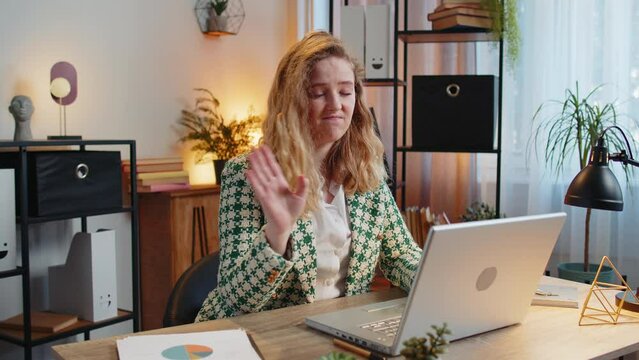 Young Caucasian businesswoman working on laptop shakes finger and saying No be careful scolding and giving advice to avoid danger mistake disapproval sign at home office. Freelancer woman at table.