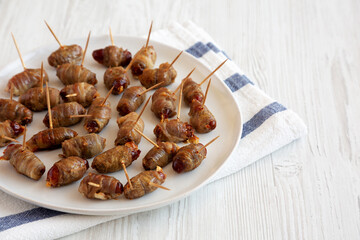 Homemade Bacon Wrapped Dates on a Plate, side view. Copy space.