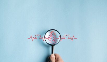 Magnifying glass over heart with electrocardiograms, life insurance heart care concept, world heart...
