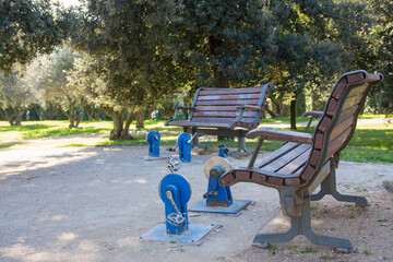 A bench and pedaling on a gymnastics apparatus in a public park.