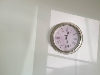 Clock on white wall with window shadow