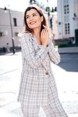 Obraz premium Portrait of young beautiful brunette woman wearing nice trendy plaid suit jacket. Sexy smiling model posing in the street at sunny day. Fashionable female outdoors. Cheerful and happy.