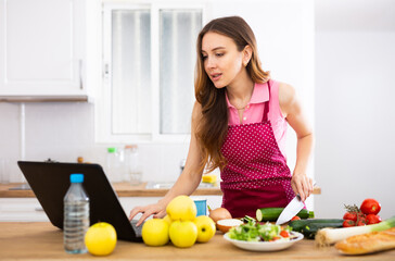 Obraz na płótnie Canvas Woman cooking salad recipe from the Internet