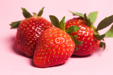 several fresh red strawberries on a pink background