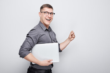 Joyful businessman manager programmer holds a laptop in his hands and smiles on a white background.