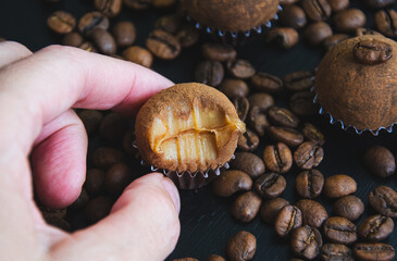 Um brigadeiro de café delicadamente na mão disposto em uma base de forminha marrom, adornado com...