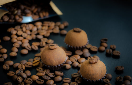 Um brigadeiro de caf&eacute; delicadamente disposto em uma base de forminha marrom, adornado com gr&atilde;os de caf&eacute;, em meio a uma decora&ccedil;&atilde;o. A coffee brigadeiro delicately arranged in a brown base.