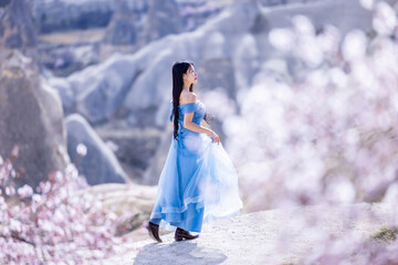 Beautiful woman in blue dress on rocks mountain. Cheerful woman relax outdoor with beautiful sky...