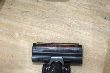 Top view of an upright vacuum cleaner head, vacuuming a wooden floor.