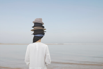 surreal woman from behind wears countless hats on her head, abstract concept - 747994088