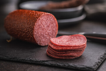Smoked salami sausages on black table.