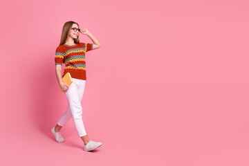 Fototapeta na wymiar Full length profile portrait of positive smart girl hand touch eyewear hold book walk empty space isolated on pink color background