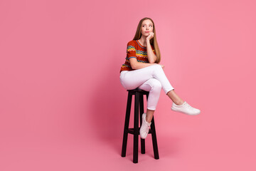 Full size portrait of minded unsatisfied girl sit stool look empty space isolated on pink color...