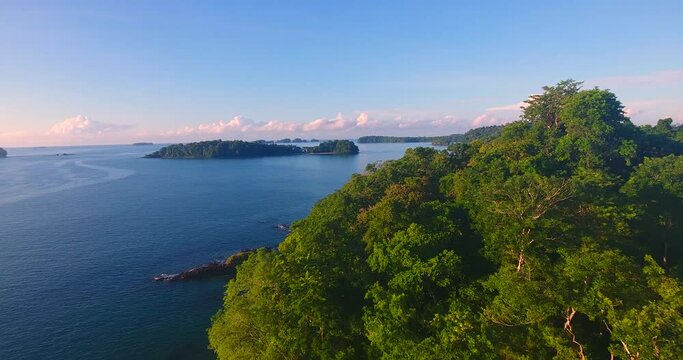 Flying low over the tree-filled forest on a peninsula that is part of the Isla Paridas in Panama to reveal a calm water bay with no boats anchored