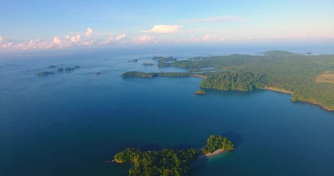 Flying high above the many Parida Islands in Panama looking at the dark blue Pacific Ocean out to the cloud-covered horizon