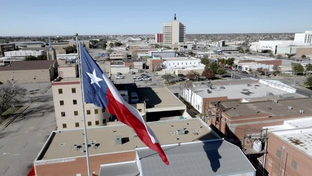 Texas state flag waving in the wind in Odessa, Texas with drone video moving forward.