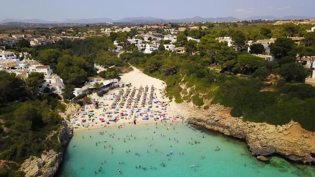 Cala anguila beach with sunbathers and swimmers, vibrant turquoise water, summer vibe, mallorca, aerial view