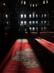 Red embroidered carpet in mosque with sun rays coming through the window, muslim religion