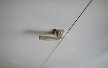 Close-up of stainless steel doorknob on white door. Macro shot of interconnecting doorway. Detail of house furniture. Home interior and renovation concept
