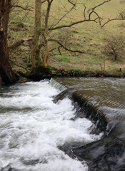 Side view of a waterfall on the River Dove in winter, Derbyshire England
