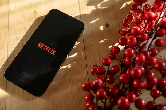On the table is an iPhone 14 Pro Max smartphone with the Netflix app on the screen. Top view. Netflix is one of the most popular global streaming movie providers. Budapest, Hungary. November 2023.