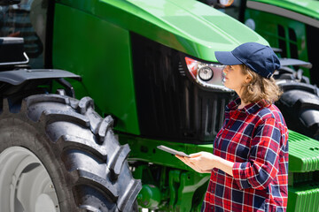 Woman farmer with a digital tablet next to agricultural tractor