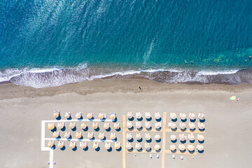 Top view aerial drone photo of black Perissa beach with beautiful turquoise water, sea waves and...