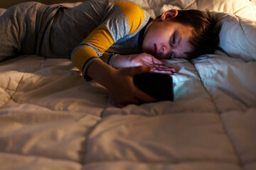 Cropped shot of a young boy sleeping with a cellphone in hand at home.