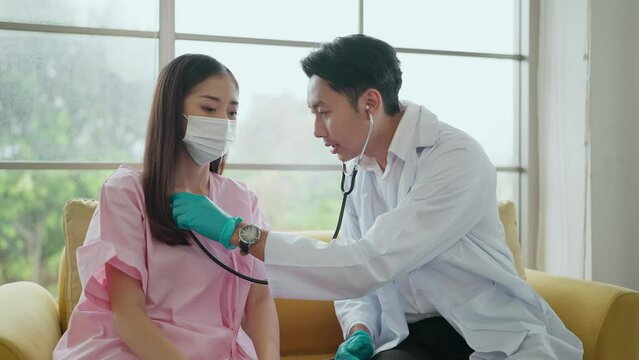 Asian male doctor using stethoscope, listening to female patient breath or heartbeat checking for any abnormalities while consulting. Healthcare and medical concept