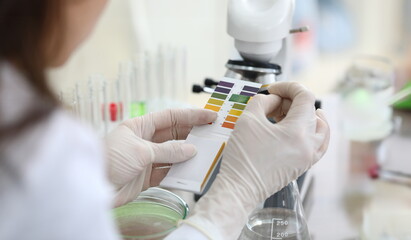 Close-up of scientists hands comparing test colors with samples. Chemist making experiment in...