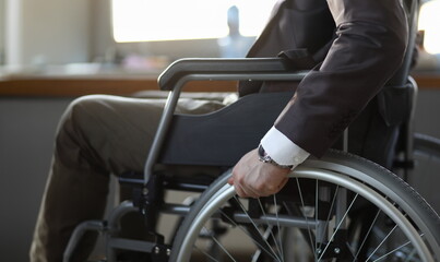 Fototapeta premium Close-up of disabled man on wheelchair in office wearing presentable suit. Adaptation of people with disabilities in society. Recovery and healthcare concept