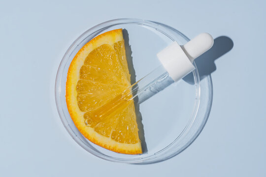 Petri dish with orange slice and cosmetic pipette. Skin care citrus acids research. Skin care products testing
