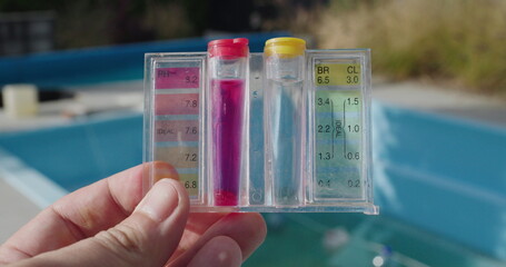 A man holds a tester for PH and chlorine levels against the backdrop of a swimming pool. Water Quality Testing