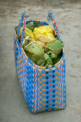 Colorful woven basket, shopping bag filled with groceries wrapped in banana leaves. Southeast Asia.