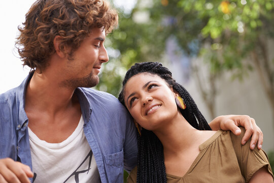 Couple, interracial and smile in nature with love, together and romantic relationship with care for growth. Outdoor, sitting in garden, diversity and joyful expression in happiness development