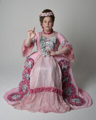 Fun length portrait of female model wearing an opulent pink gown, costume of a historical French...