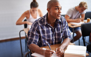 Black man, student and writing with book in classroom for studying, reading or summary at...