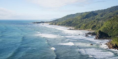 Rough exotic coast with azure ocean water, big waves and rainforest vegetation, New Zealand
