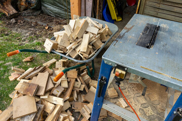 Circular saw with cut firewood in the background in a wheelbarrow