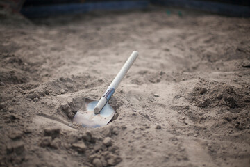 A shovel in the sandbox. A sapper shovel. A shovel with a wooden handle. Children's shovel for playing in the sandbox