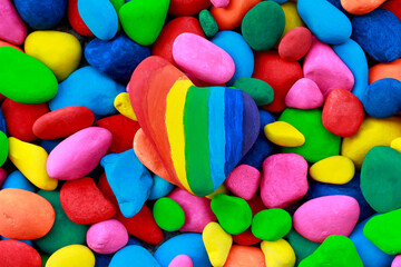 Rainbow painted stone heart among multi colored pebbles
