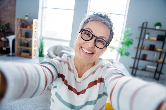 Portrait of positive aged person toothy smile take selfie record video free time modern spacious apartment inside