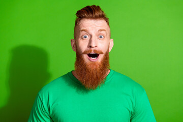 Photo of impressed man with long ginger beard dressed green t-shirt astonished staring at discount isolated on green color background
