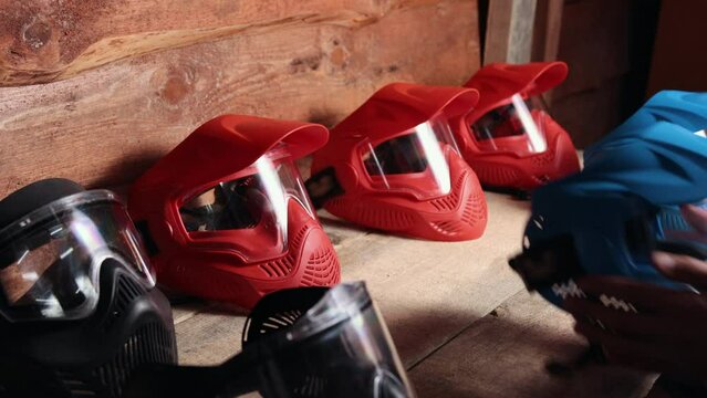 protection masks, Paintball combat, Game gear. Row red and blue paintball masks, carefully arranged on wooden shelf, Before starting game, player takes mask from shelf.