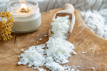 Candle wax flake in wooden spoon. Tools and elements for a handmade organic scented candle