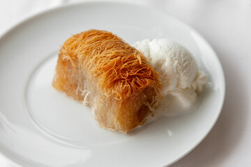 Traditional greek dessert kataifi served with ice cream on a white plate. - 748051211