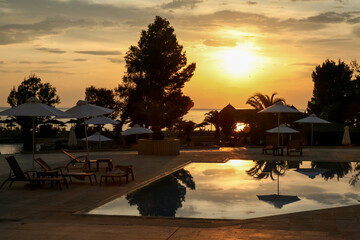 Sunrise view of a pool in a hotel somewhere at  mediterranean sea, sky reflecting in a pool. - 748051215