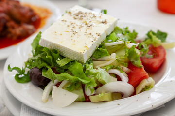 Traditional greek salad with a slice of feta cheese and olives  served in tavern in Halkidiki, Greece. - 748051240
